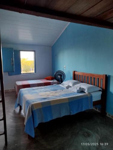 a blue bedroom with two beds and a window at Eco Pousada Tigipió in São Mamede