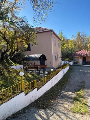 a house with a yellow fence next to a road at Vələs Garden in Quba
