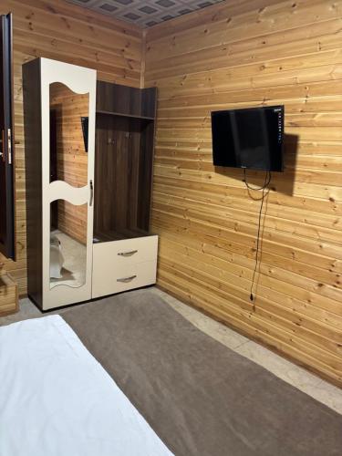 a room with a flat screen tv and a bed at Vələs Garden in Quba