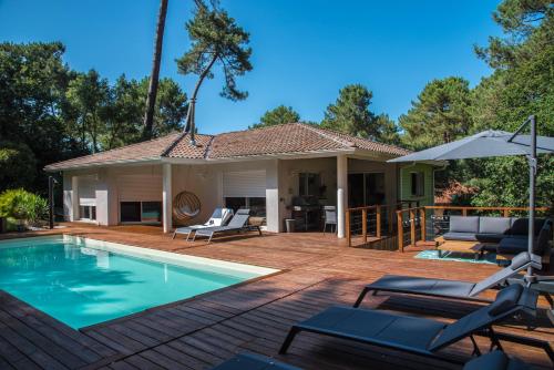 a patio with a swimming pool and a house at Connemara, Superbe Villa avec piscine, au cœur de la forêt, accès à la plage en vélo in Soorts-Hossegor