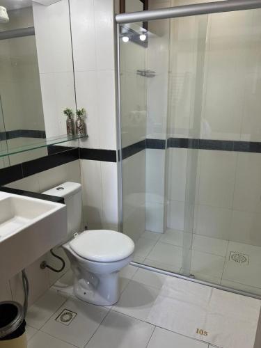 a bathroom with a toilet and a glass shower at Kariri Beach Residence in Caucaia