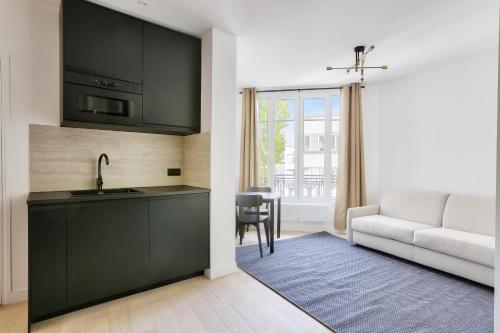 Il dispose d'une cuisine avec un évier et d'un salon avec un canapé. dans l'établissement Appartement 2 Pièces I 8 min à pied de la Défense, à Courbevoie