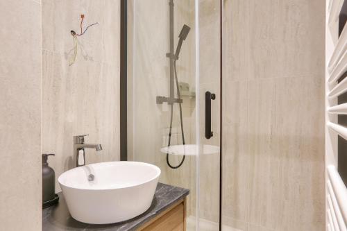 une salle de bain avec un lavabo blanc et une douche dans l'établissement Appartement 2 Pièces I 8 min à pied de la Défense, à Courbevoie