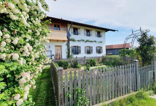 a fence in front of a white house with roses at Springerhof in Schechen
