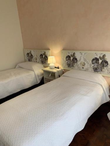 a bedroom with two beds and a table with a lamp at La casa dei pini in Malnate
