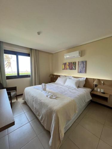 a bedroom with a large white bed and a window at Kariri Beach Residence in Caucaia