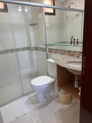 a bathroom with a toilet and a shower and a sink at Kariri Beach Residence in Caucaia