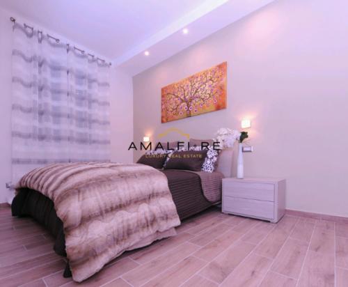 ein Schlafzimmer mit einem Bett und einem Gemälde an der Wand in der Unterkunft Casa Serena in Amalfi