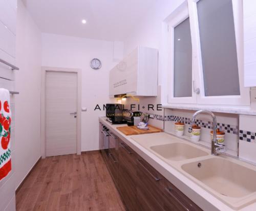 eine weiße Küche mit einer Spüle und einer Theke in der Unterkunft Casa Serena in Amalfi