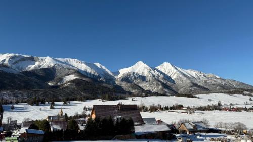 a snow covered mountain range with a house in the foreground at Penzión Soňa in Ždiar