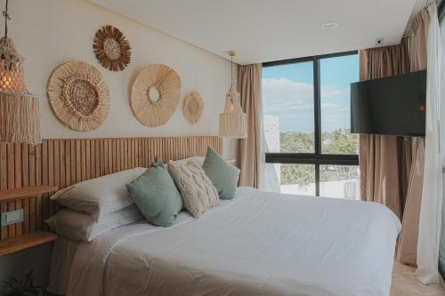 a bedroom with a white bed with pillows and a window at Casa Reina Tulum in Tulum