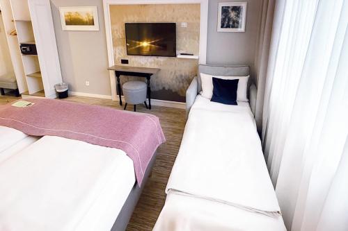 a room with two beds and a desk in it at Garner Hotel Berlin - Wilmersdorf by IHG in Berlin