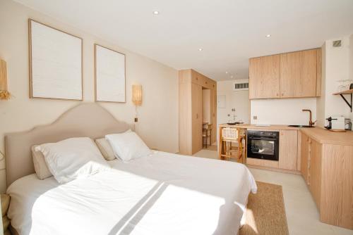 Cet appartement comprend une chambre avec un lit blanc et une cuisine. dans l'établissement Studio rénové avec vue mer, à Grimaud
