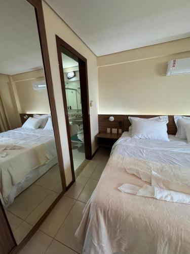 a bedroom with two beds and a large mirror at Kariri Beach Residence in Caucaia