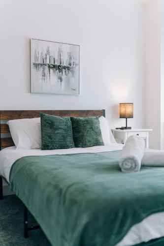 a bedroom with a large bed with a green blanket at 3 Bedroom House Workstays UK in Middlesbrough