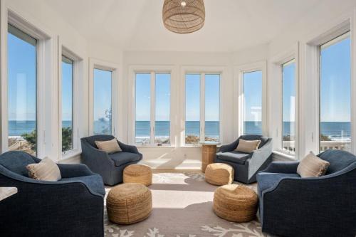 a living room with chairs and windows with the ocean at Beachfront Bliss with Pool & Hot Tub in Corolla