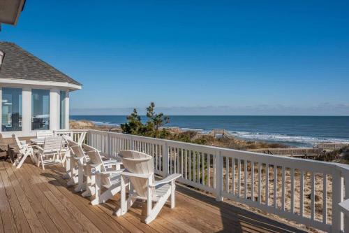 a deck with white chairs and the ocean at Beachfront Bliss with Pool & Hot Tub in Corolla