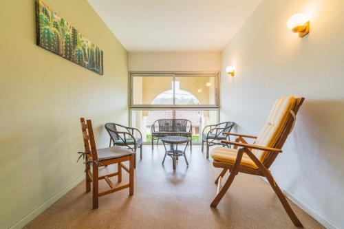 a living room with chairs and a table and a window at Les Mimosas - App 06 - Appartement Cosy RDC in Cazaubon