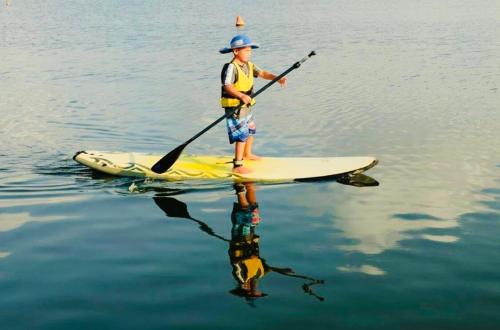 a boy standing on a paddle board in the water at Inbal's suite, Caesarea in Caesarea