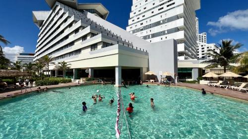 a group of people in a swimming pool in front of a building at Luna, 2 Beds en la mejor ubicación de Cancún in Cancún