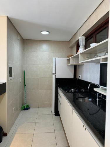 a kitchen with a black counter and a sink at Kariri Beach Residence in Caucaia