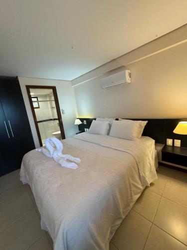 a bedroom with a large white bed with towels on it at Kariri Beach Residence in Caucaia