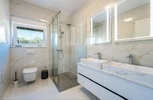 a bathroom with two sinks and a shower and a toilet at Villa Adria Maria 2 in Privlaka