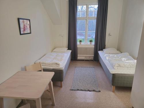 a room with two beds and a table and a window at Ronneby Brunnspark Vandrarhem och B&B in Ronneby