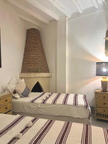 a bedroom with two beds and a brick fireplace at Riad Jnan El Cadi in Marrakech