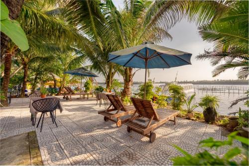 a patio with chairs and a table with an umbrella at Sunset Beach Hoi An in Tân Thành (1)