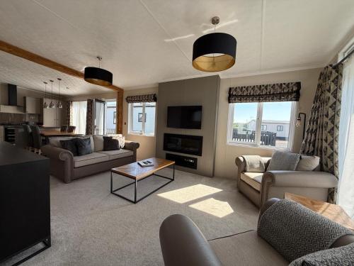 a living room with couches and a table in it at Luxury Lodge Retreat with Hot Tub - Stewarts Resort 19 in St. Andrews