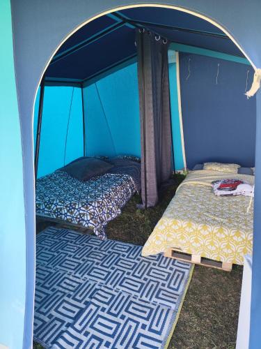 une chambre avec deux lits dans une tente dans l'établissement La Billardière Camping à la Ferme, à Le Ménil-Ciboult
