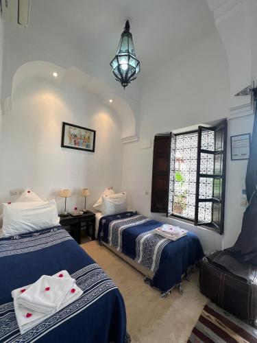 a bedroom with two beds and a chandelier at Riad Jnan El Cadi in Marrakech