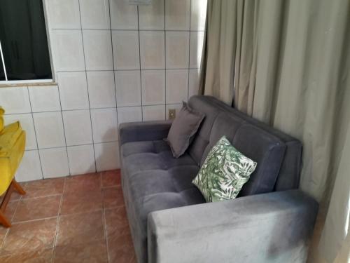 a blue couch with two pillows on it in a room at Casa e Kitnet - Praia Grande Centro in Arraial do Cabo