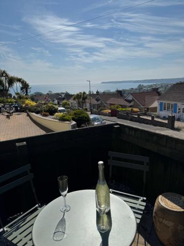 a table with a wine bottle and two glasses on a balcony at Primley View in Goodrington