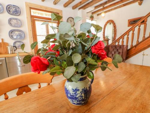 a blue and white vase with red roses on a table at Shaftoe Mews in Hexham