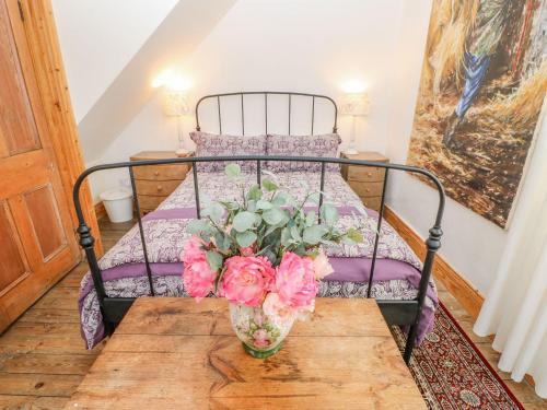 a bed with a vase of flowers on a table at Shaftoe Mews in Hexham