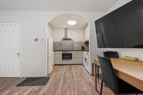 a kitchen with a wooden table and a large television at BTS 2 Bed Apart Inverness Centre in Inverness