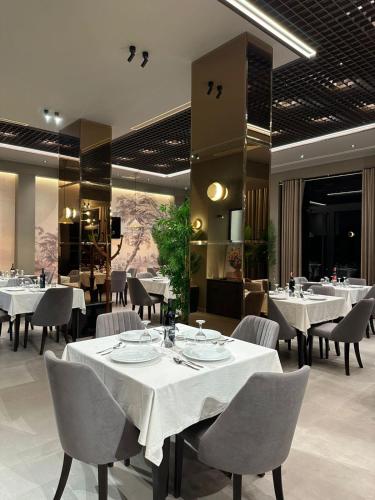 jadalnia z białymi stołami i krzesłami w obiekcie New Donantelo Hotel we Wlorze