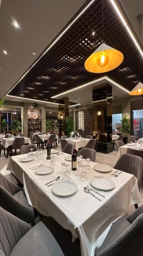 jadalnia z białymi stołami i krzesłami w obiekcie New Donantelo Hotel we Wlorze