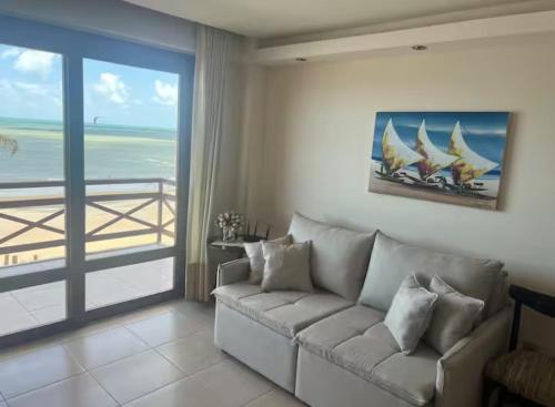a living room with a couch and a view of the ocean at Kariri Beach Residence in Caucaia