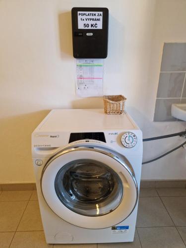a washing machine in a room with a sign on the wall at penzion U losa in Spořice