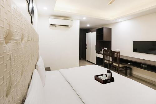 a bedroom with a white bed and a television at Super Townhouse The AMV Hotel in Gurgaon