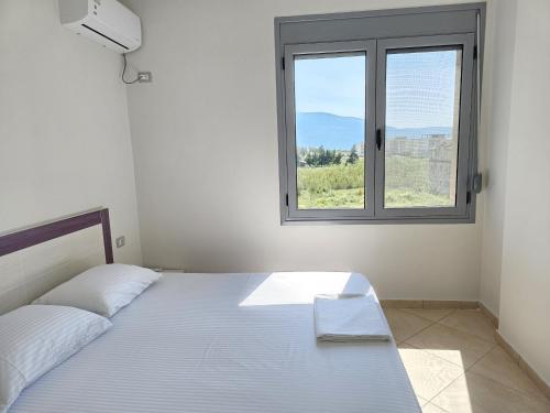 a white bedroom with a bed and a window at Apartment With Pool View In Rradhime in Vlorë