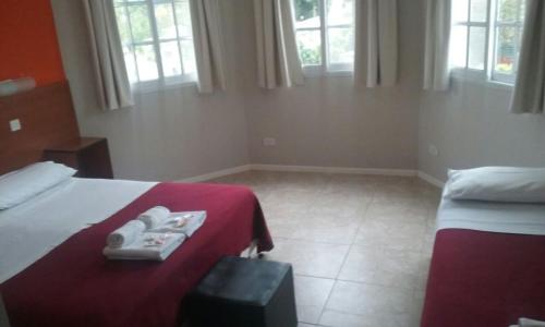 a bedroom with two beds and a red blanket at Hotel Queguay in Colón