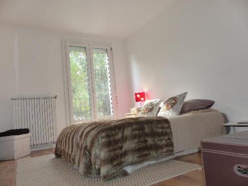 une chambre avec un lit avec une couverture et une fenêtre dans l'établissement Agréable appartement Montfavet Avignon, à Avignon
