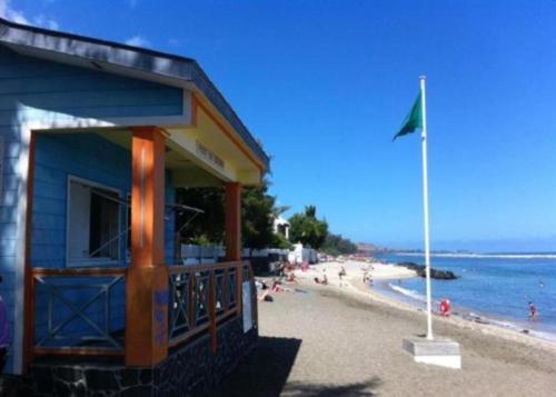 a blue building on a beach with a flag at Villa des Filaos et du lagon o6, 93 , 70 , 59 , 79 in Saint-Leu