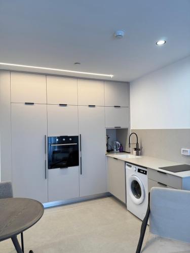 a kitchen with white cabinets and a washing machine at ירדן דירת גן אדריכלית סוויטה פרטית in Eilat