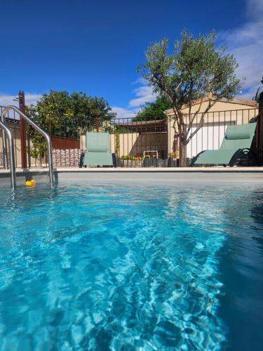 a swimming pool with clear blue water and chairs at Le Rubiz in La Coucourde