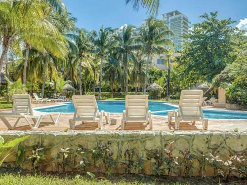 a group of lounge chairs in front of a swimming pool at Tropical 3 BDR Villa with pool By Casa Paraíso in Cancún